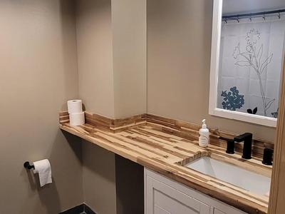 Full bathroom with butcher block vanity and dark tile