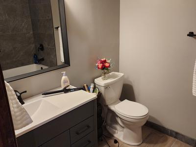 Full bathroom with dark vanity and wood-look tile floor