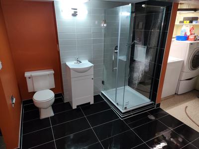 Bathroom with glossy black tile and glass corner shower