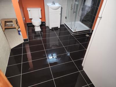 Black tile floor with glass corner shower enclosure