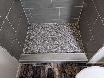 Pebble stone shower floor with gray tile walls