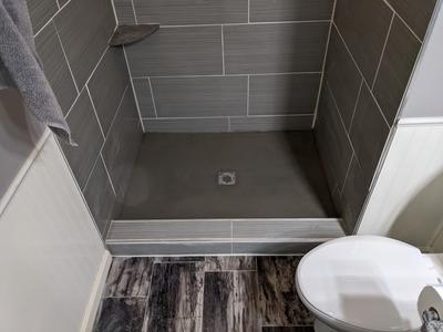 Gray tile walk-in shower with corner shelf