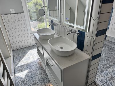 Farmhouse bathroom vanity with dual vessel sinks and encaustic floor tile