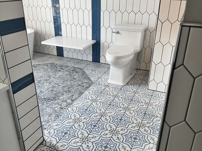 Pebble stone shower floor with open walk-in design and freestanding tub beyond