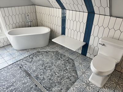 Freestanding soaking tub with hexagonal wall tile and encaustic floor