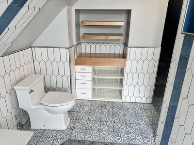 Farmhouse bathroom with built-in shelving cabinet and patterned tile floor