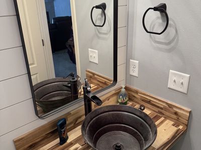 Vessel sink on butcher block vanity with shiplap walls and matte black fixtures