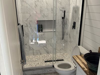 Full bathroom with shiplap walls and marble tile shower