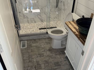 Marble shower with glass door and shiplap accent wall