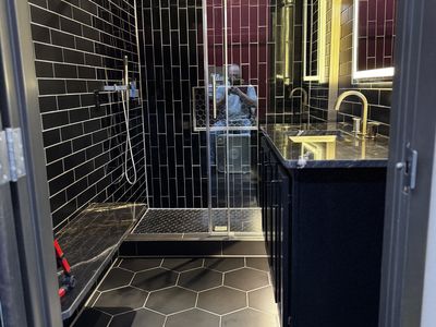 Bold black vertical subway tile bathroom with matte black fixtures and marble vanity top