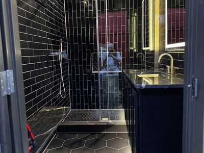 Black tile shower with hexagonal floor and built-in niche