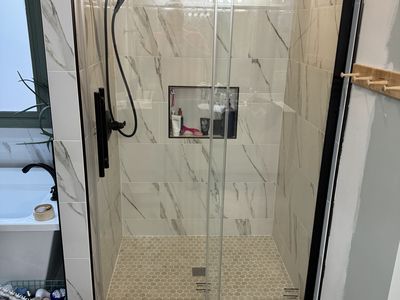 Marble-look tile shower with glass door and matte black fixtures