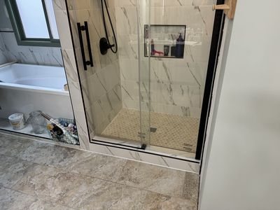 Marble tile shower interior with recessed niche and penny tile floor