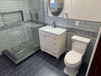 Completed bathroom with grey subway tile, glass shower and white vanity
