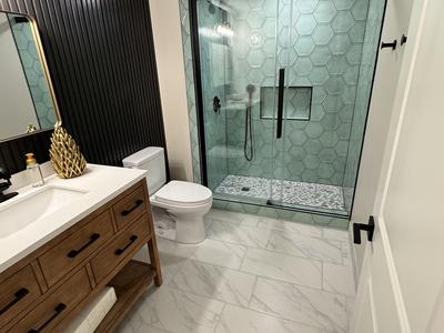 Modern bathroom with green hexagon tile shower, black slat accent wall and wood vanity