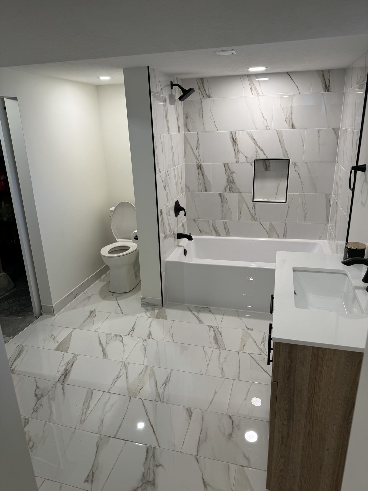 Marble-look tile tub and shower surround with matte black fixtures