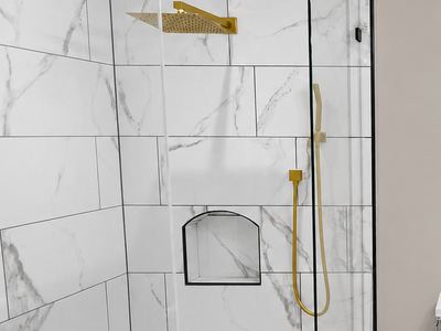 Marble tile shower with brushed gold fixtures, penny tile floor and vessel sink vanity