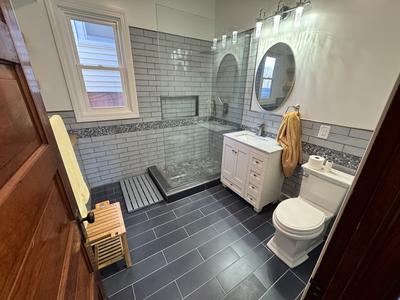 Full bathroom remodel with gray subway tile, pebble accent band and slate tile floor