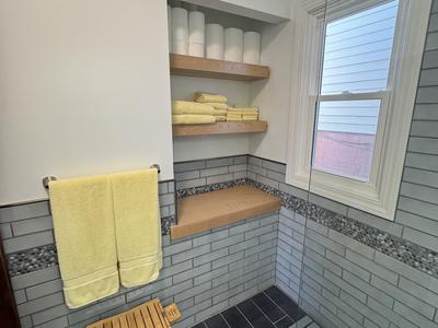 Tiled shower with pebble accent band, floating oak shelves and built-in bench