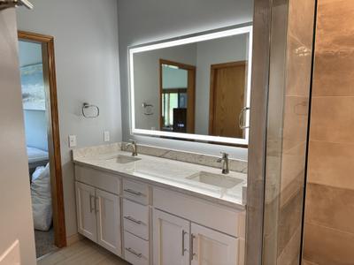 Master bathroom double vanity with backlit mirror and marble countertop