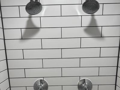 Dual shower heads on white subway tile with dark grout