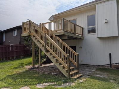 Raised wood deck with staircase from yard level