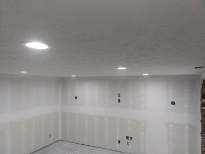 Basement drywall with textured ceiling and stone accent