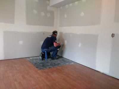 Worker hand-mudding drywall seams