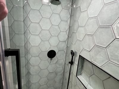 Walk-in shower with sage green hex tile