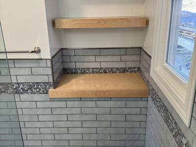 Oak floating shelves in tiled bathroom niche