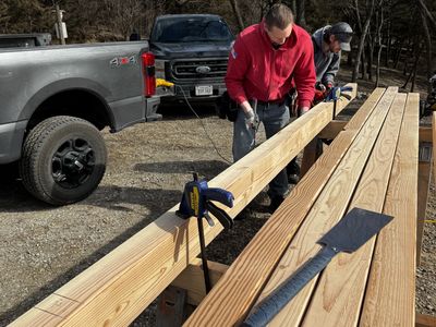 Two crew members working together on lumber — teamwork in action